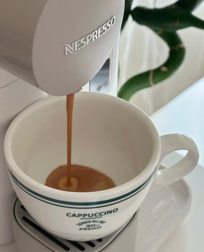 Koffie loopt uit een Nespresso-machine in een witte cappuccinokop